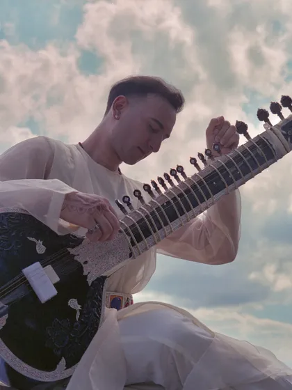 Playing my sitar under a beautiful sky. This photo connects the music to the vastness and beauty of nature.