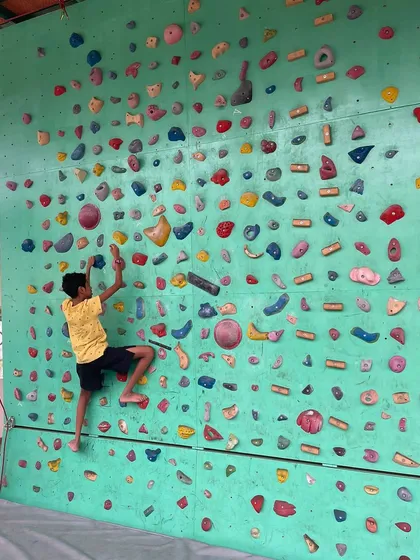 Here, a young climber navigates a bouldering route on our wall. We encourage kids to find their own path, focusing on the process of problem solving and building focus rather than just reaching the top.