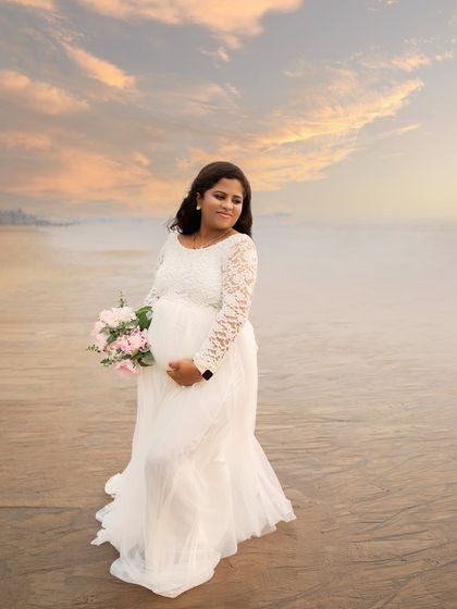 A beautiful mumma-to-be holding a bouquet of flowers against the backdrop of a dreamy sunset sky. This beach session combines romance, nature, and the glow of pregnancy.