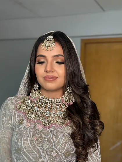 A soft glam look for a wedding ceremony or reception. I created deep, flowing waves and set them to one side for a romantic and ethereal feel that complements her pastel outfit.