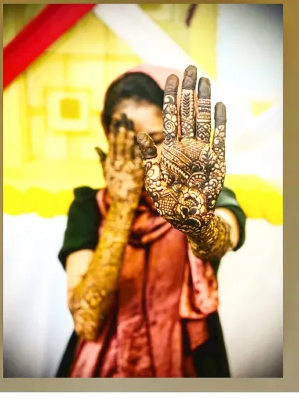 A candid moment with a bride, showing how the full-hand mehendi becomes a central part of her look. The design is intricate and covers the entire palm and fingers.