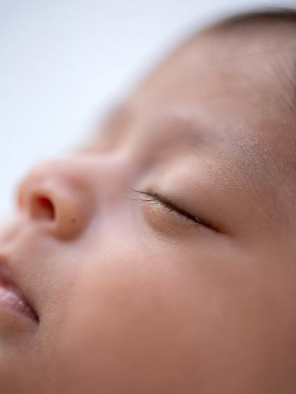 The soft flutter of newborn eyelashes against their cheek. A simple, peaceful moment captured in a detailed macro photograph.