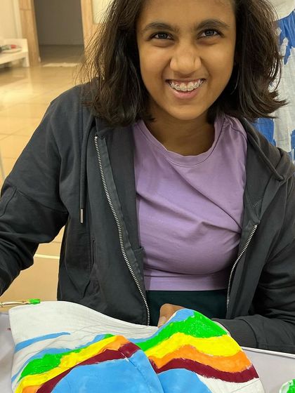 A big smile from this artist as she works on her colorful, abstract-painted bucket hat.