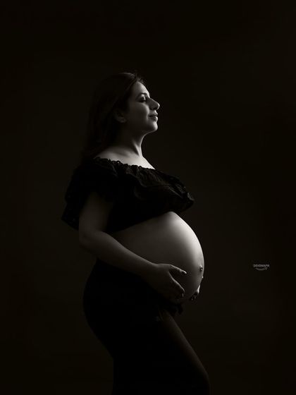 A serene and powerful bare-bump portrait using low-key lighting. This technique creates deep shadows and soft highlights, resulting in a dramatic and artistic black and white photograph.
