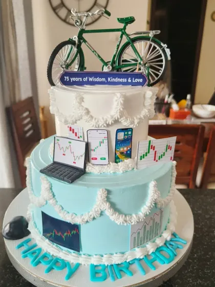A unique 75th birthday cake celebrating a love for cycling and stock trading, with a miniature bicycle on top and edible stock charts on the sides.