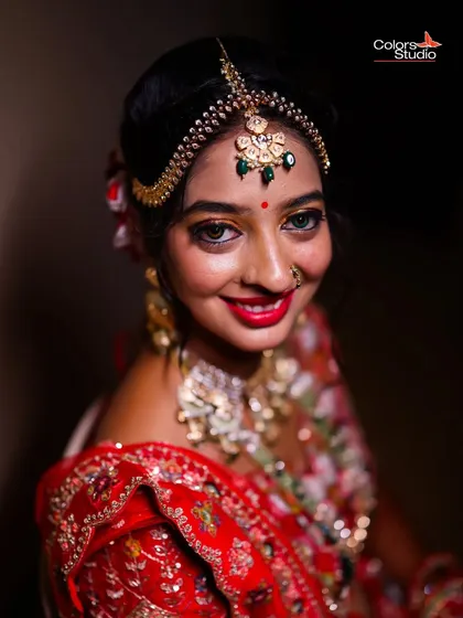 A close-up bridal portrait in a stunning red lehenga, capturing her bright smile and beautiful makeup.