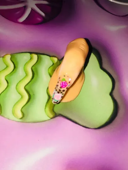 A student practicing their fine art skills on a display finger. This fun design includes tiny strawberries and dots, showing their progress in detailed brush control and creating playful patterns.