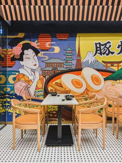 This Japanese restaurant design blends two distinct styles. One side features vibrant, graphic murals depicting iconic Japanese culture for a high-energy feel, while the other offers a calm, minimalist aesthetic for a more intimate dining experience.