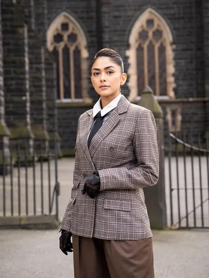 A full-length view of the androgynous suit, showing the wide-leg trousers and the overall powerful stance.
