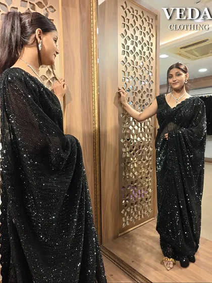 The mirror shot shows how this black saree drapes beautifully, creating a flattering silhouette.