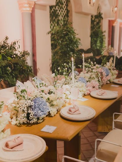A closer look at the dinner table setting, featuring soft pastel hydrangeas and simple, elegant place settings.