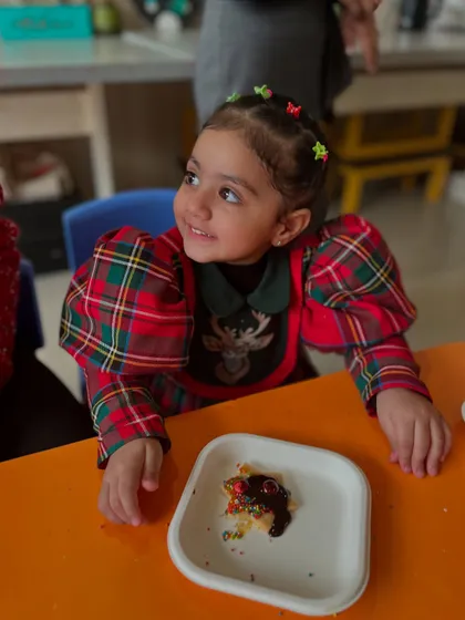 A happy girl in a festive dress enjoys her decorated cookie. The satisfaction of creating and then eating a treat is pure joy.
