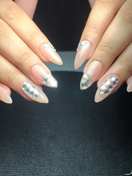 An elegant and luxurious design featuring a nude base on stiletto nails. The look is enhanced with silver mirrored crystals arranged in a sophisticated pattern on accent nails.