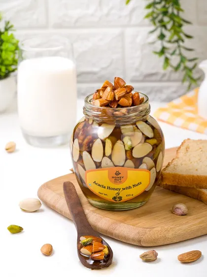 A jar of acacia honey with nuts styled for a breakfast scene with toast and milk. This helps customers visualize the product as part of their daily routine.