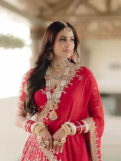 A classic three-quarter portrait of the bride, her pose exuding confidence and grace in her traditional red attire.