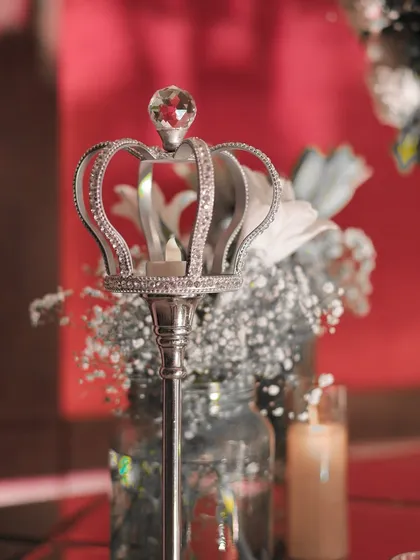 A close-up of a silver crown-shaped candle holder, a small detail that adds a touch of royalty to the welcome decor.