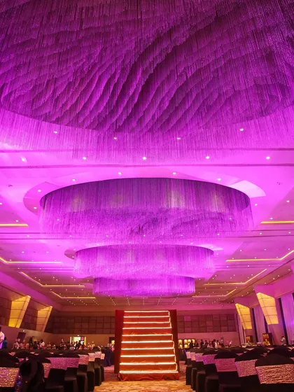 A breathtaking ceiling installation featuring thousands of shimmering strings, creating a massive, multi-tiered chandelier effect. This design element transformed the entire ballroom, adding depth, drama, and a wash of purple light.