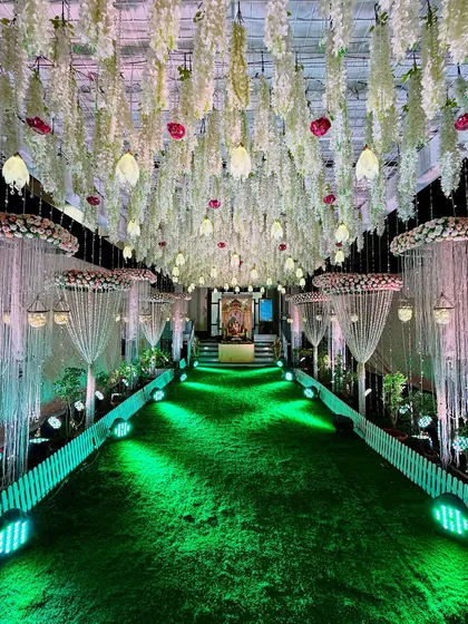 Another view of a grand royal passage, with a ceiling of hanging florals and crystal strings. The green turf path is lit to create a dramatic and enchanting entrance for a night-time reception.