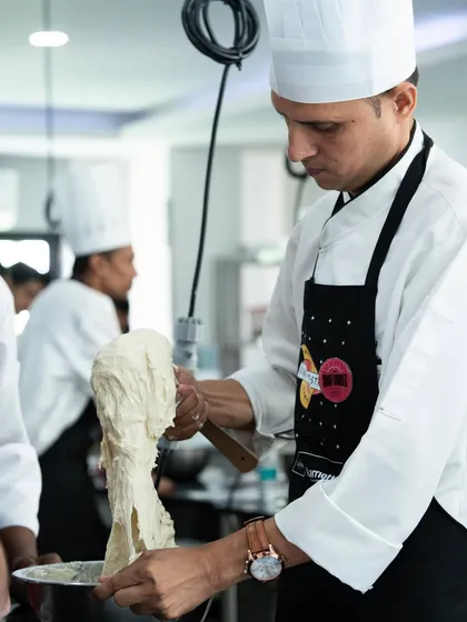 A chef from a Marriott property handles a delicate dough, demonstrating the hands-on nature of our symposia.