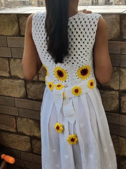 A back view of the sunflower frock, showing the detailed crochet work and the tie-back belt. It’s designed for both beauty and comfort, allowing plenty of room for play.