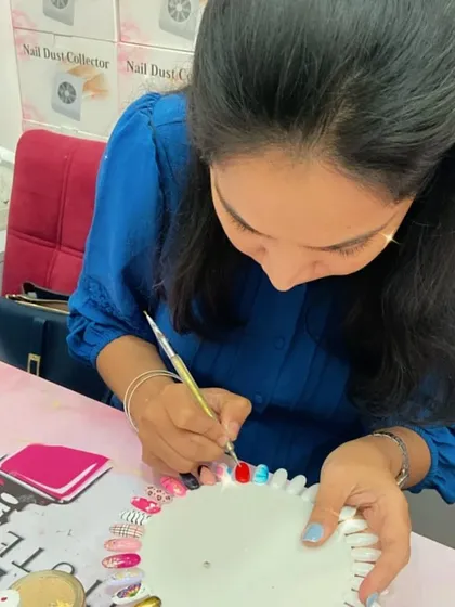 A student adds a pop of color to her practice wheel, learning how to create vibrant and eye-catching nail art.