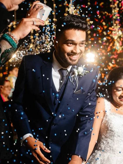 A shower of colorful confetti rains down on the smiling bride and groom as they make their entrance.