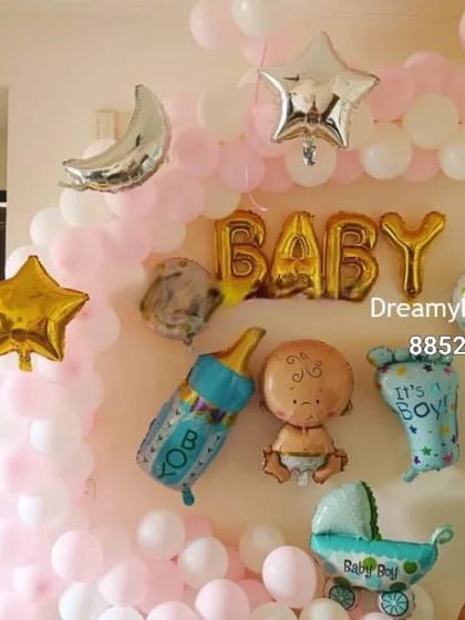 This wall decoration is great for a baby's room or a small celebration. It features a pink and white balloon arch, star and moon foil balloons, and various baby-themed foil characters like a bottle and carriage.