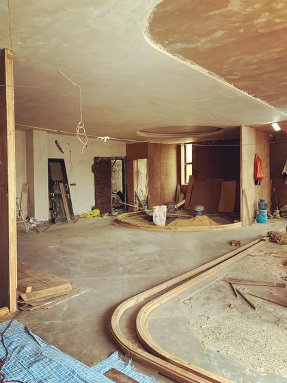 The interior of a micro-office taking shape, with curved wooden partitions and ceiling details. The design uses a rich palette of wood to create a warm and dynamic workspace.