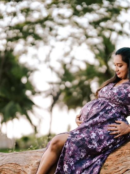 A lovely profile shot of an expecting mother cradling her bump, with the soft light of the outdoors creating a gentle and warm atmosphere.