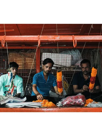 4:27am: Three men sit together in the pre-dawn hours, skillfully weaving vibrant marigold garlands for the morning temple rush. An intimate look at the unseen labor that fuels the city's spiritual life.