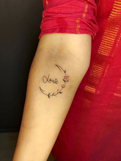 A crescent moon made of flowers with a name scripted inside. This is a beautiful and popular design for those who want something both personal and decorative.