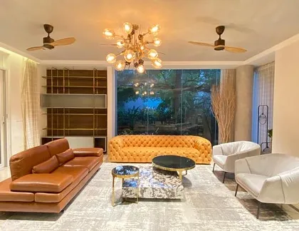 We furnished this entire breathtaking living room to create a symphony of style and sophistication. The space features a bold, tufted chesterfield in mustard yellow, a sleek leather sofa, and a set of unique marble coffee tables, all working together to create an environment that is both grand and inviting.