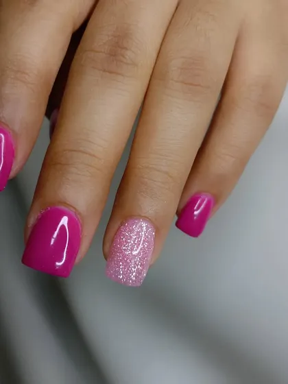 A dip powder manicure in a beautiful magenta, with a sparkling pink glitter accent nail.