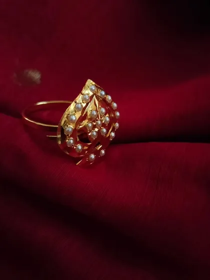 The 'पर्ण' (Parn) gold-plated Jadau adjustable ring. This leaf-shaped ring with pearls is a delicate and elegant choice.