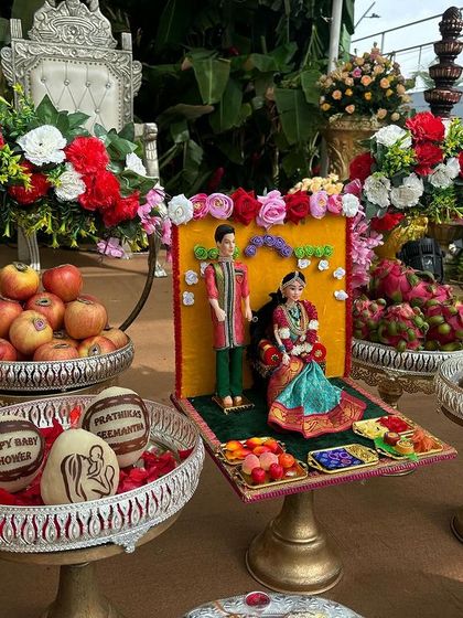 A personalized offering for a baby shower, with custom-carved coconuts and dolls representing the couple.