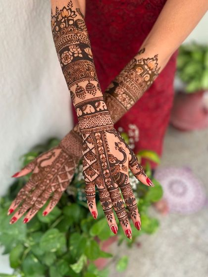 A different angle of the portrait mehndi, showing the peacock and other traditional elements on the arms.
