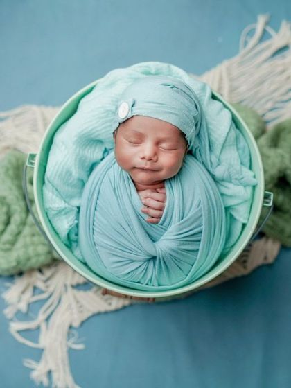 A smile in their sleep. This overhead shot of a baby swaddled in a bucket is a classic and adorable pose.