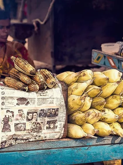 A street vendor sells roasted and fresh corn from her cart in Hampi. This photo captures the textures and colors of a typical market scene, showing a slice of everyday life and local culture.