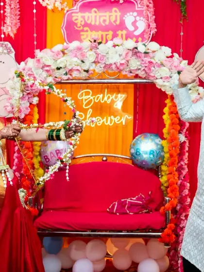 A fun and playful moment from a traditional baby shower. The mom-to-be playfully aims a bow and arrow at her partner, surrounded by festive decorations.