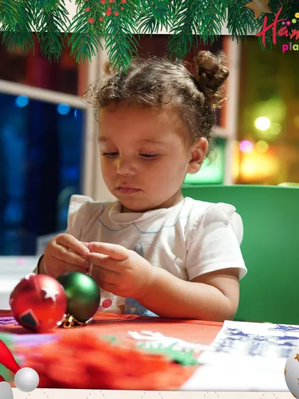 A little girl delicately works on her Christmas bauble, a look of deep concentration on her face. These quiet, creative moments are just as important as the energetic play.