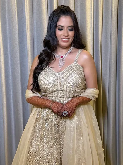 A full-length view of the bride in her dazzling gold gown. The makeup is glamorous and ready for a night of celebration.