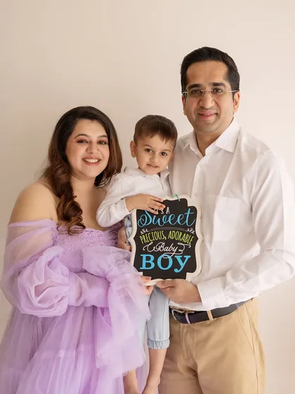 A joyful family announcement! This family of three is excited to become four, and the sign they hold adds a fun, personal touch to their maternity shoot.
