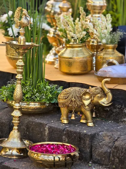 The essence of South Indian wedding decor. This arrangement features traditional brass elements like a 'diya' (lamp) and an elephant statue, softened by fresh tuberose and lotus petals.