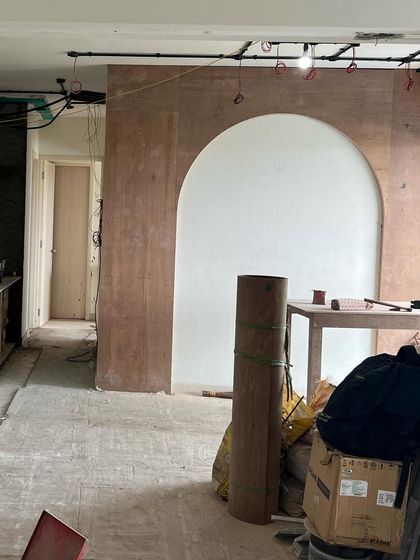 This work-in-progress shot shows the early stages of construction. The raw brick and plywood archway are the first steps in building the structural and decorative elements that will define the character of the home.