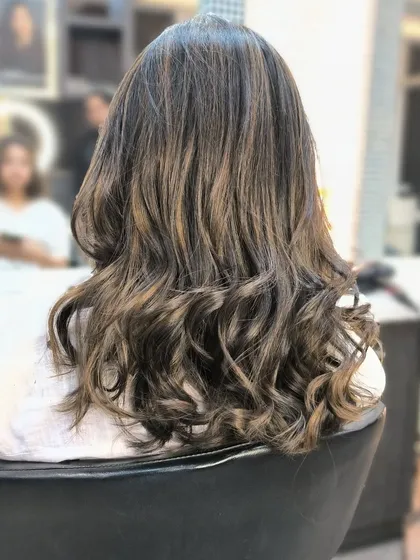 A beautiful example of global highlights on long, healthy hair. The mix of light and dark tones creates a natural-looking texture, styled here with soft waves.