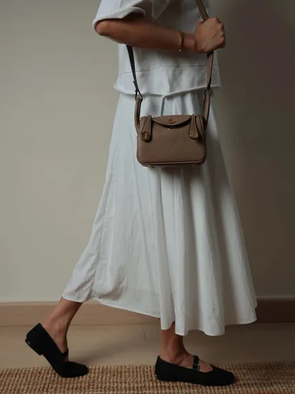 A side profile of the Linde Mini in taupe, worn as a crossbody bag. It sits perfectly on the hip, making it a comfortable and stylish choice for when you're on the move.