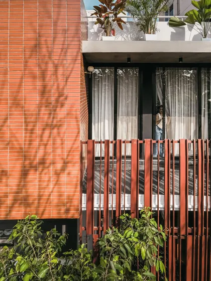 The interplay of materials is central to our design. Here, the warm red of the brick wall contrasts with the cool grey of the concrete and the deep tones of the metal screen.