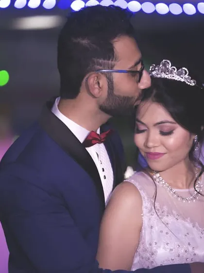 A tender forehead kiss. This is a classic, romantic portrait from a Christian wedding reception, capturing the couple's love and the magical ambiance of the evening.