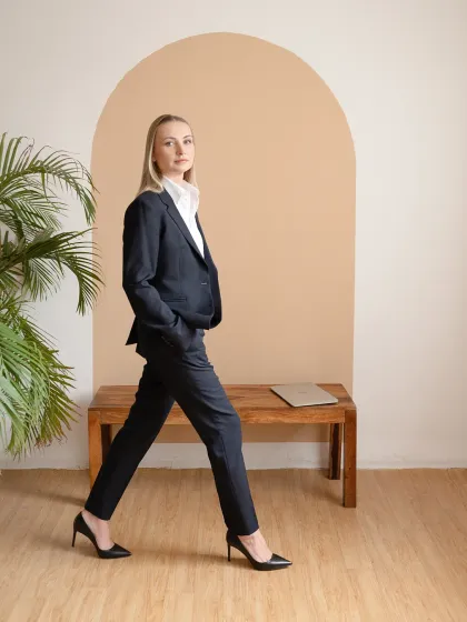 A professional portrait for a business leader, set in a minimalist studio. The focus is on conveying confidence and approachability through clean lines, natural posture, and direct engagement.