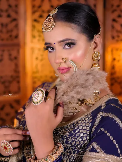 A close-up portrait of the bride in a blue lehenga, using a prop to create a soft, artistic effect.